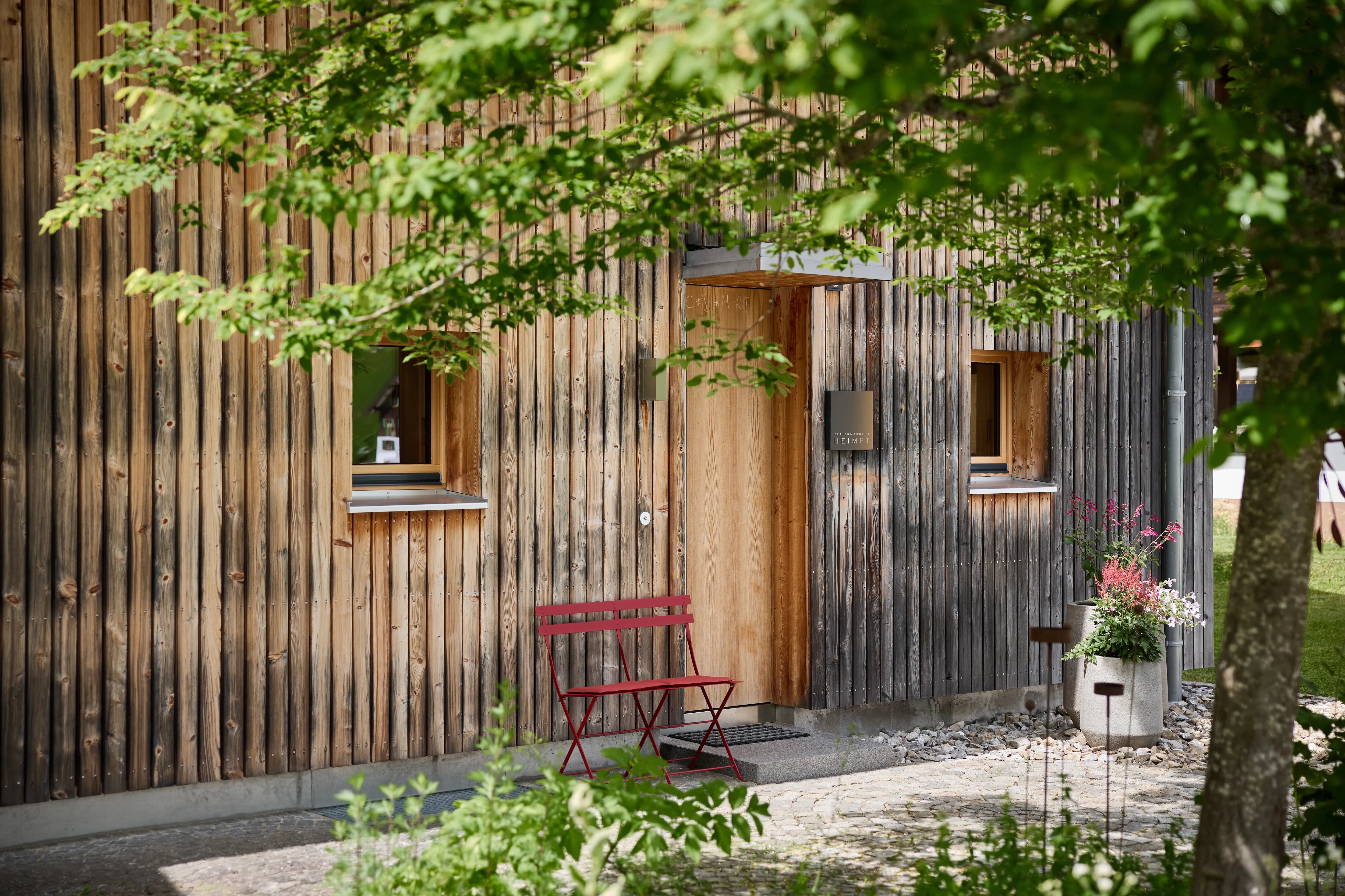 Wohnbereich mit Sofa, Bouclé-Sessel und Holzwand aus heimischem Holz